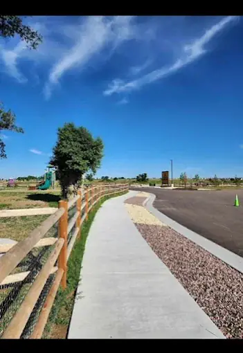 Paved walking path and playground under a blue Colorado sky